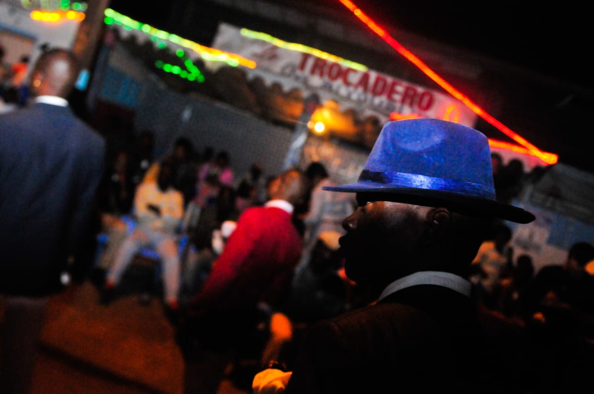 Untitled  Image: Night scene with a man on the forefront wearing a blue hat, in front of the club Trocadero in Avenue Matsoua. The Trocadero is one of the most popular clubs of Brazzaville. Congo (2008)