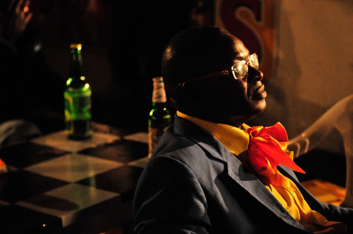 Untitled  Image: Man sitting sideways at a nightclub wearing a red bowtie and a blue jacket. Brazzaville, Congo (2008)