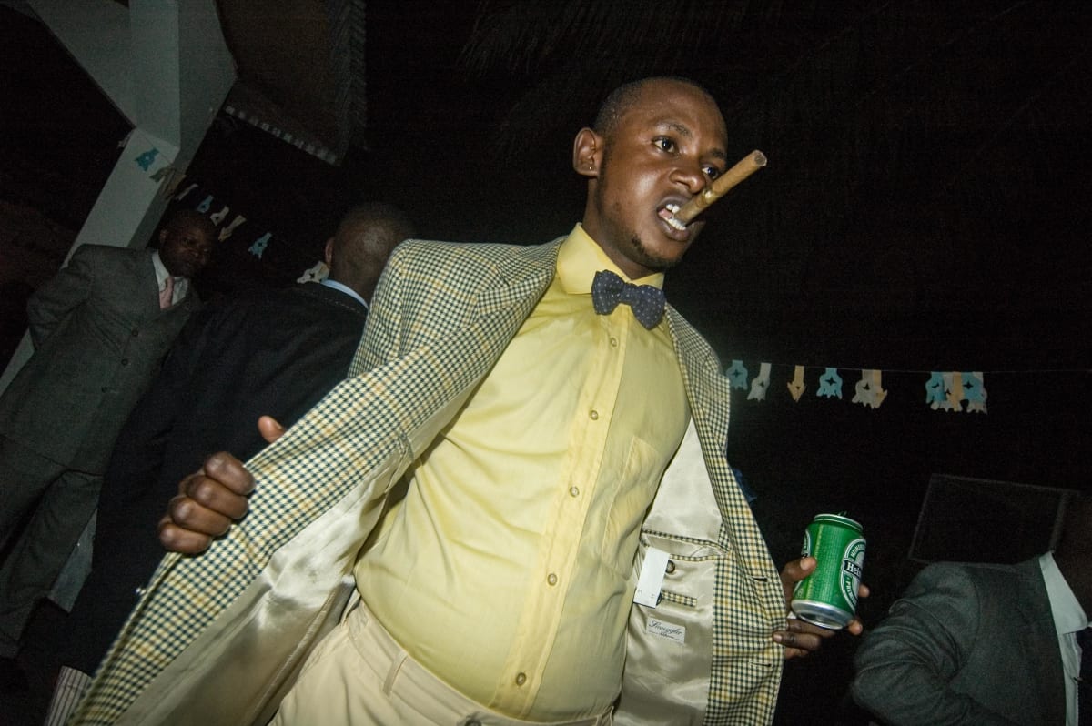 Untitled  Image: Lalhande at the nightclub Main Bleu showing off his outfit whilst holding a cigar between his teeth. Brazzaville, Congo (2007)