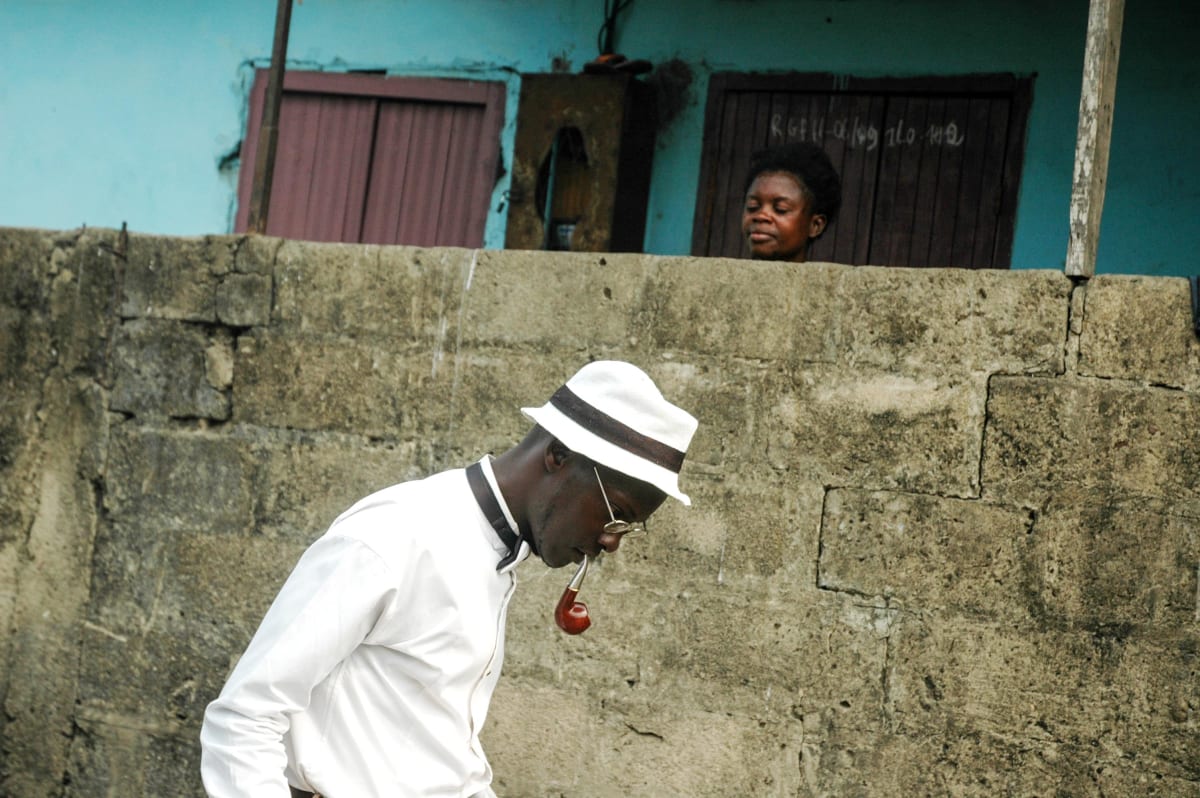 Untitled  Image: Michel walking down the streets with a kid peeking at him over a wall. Brazzaville, Congo (2007)