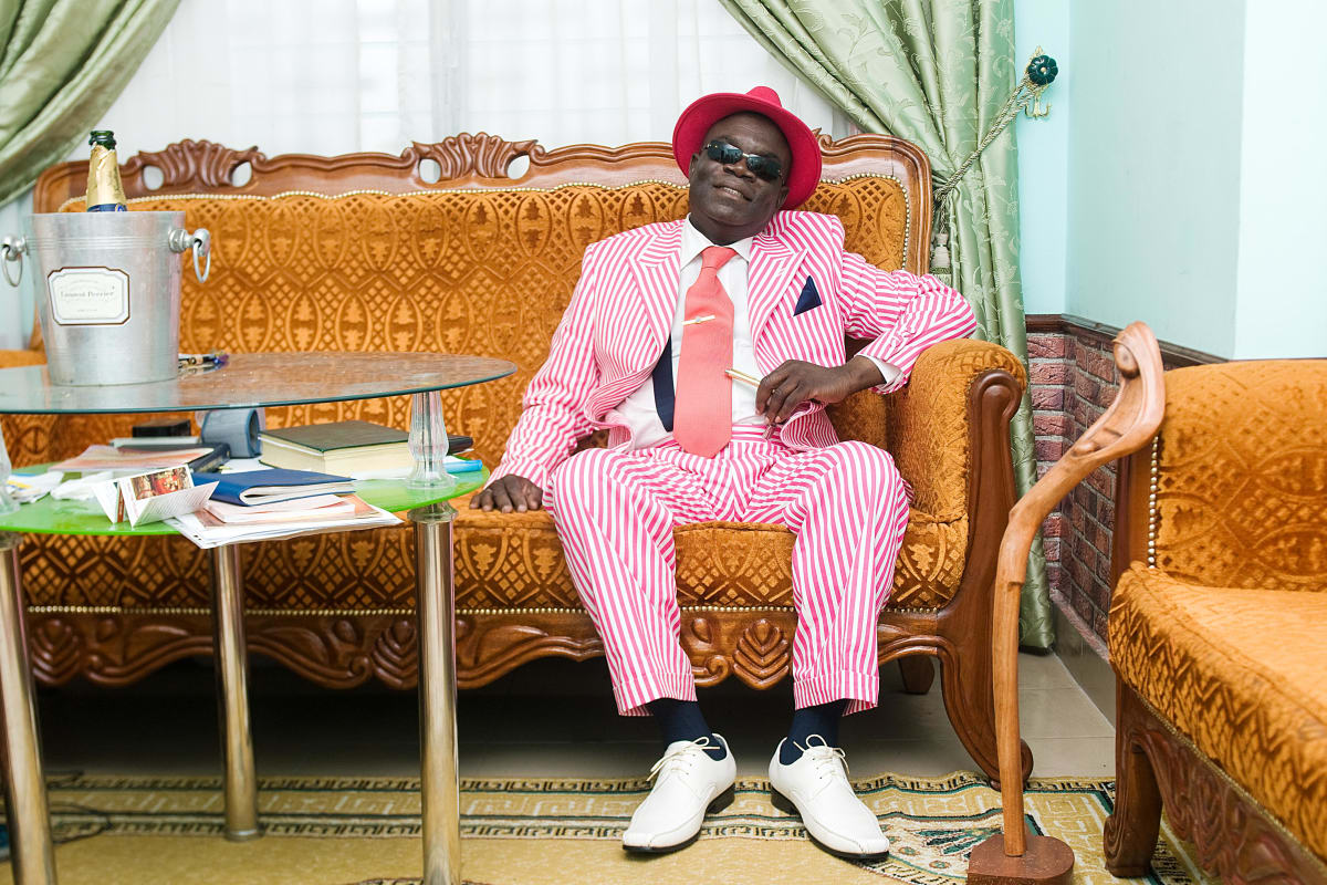 Untitled (The Chalereux Abbot)  Image: Anselme Badiamo sitting on his couch wearing a pink pinstriped suit and a hot pink hat. Brazzaville, Congo (2008)