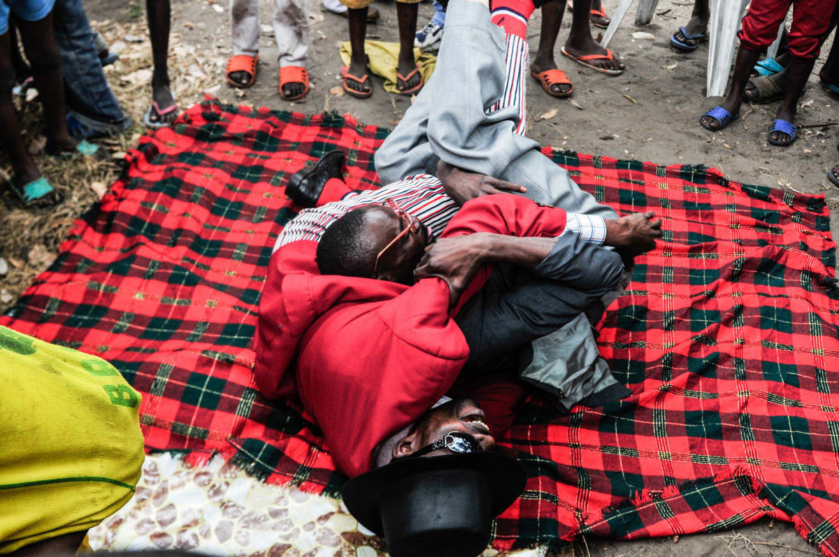 Untitled (Rough-and-Tumble)  Image: Two Sapeurs playing rough-and-tumble on a blanket on the floor, surrounded by a group of kids. Brazzaville, Congo (2008)