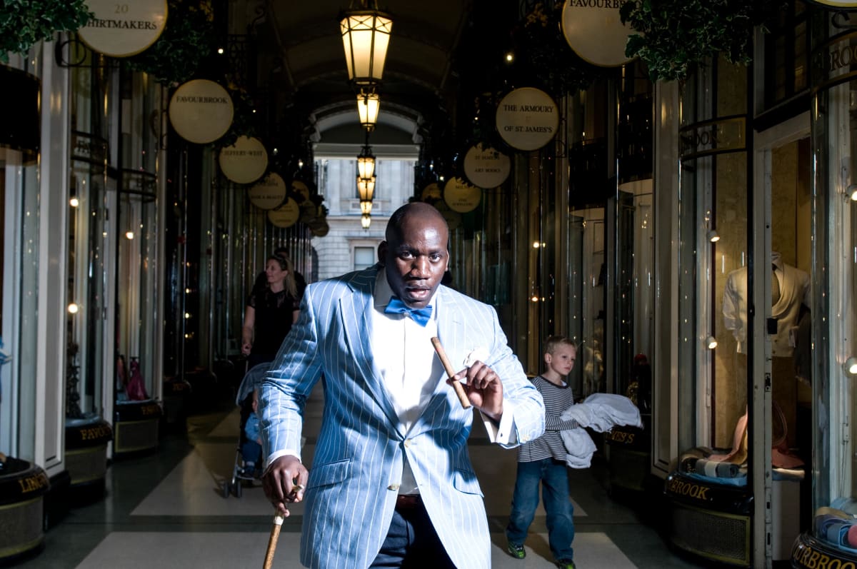 Untitled  Image: Dixy Ndalla walking the streets of London with his walking stick, holding a cigar. London, UK (2009)