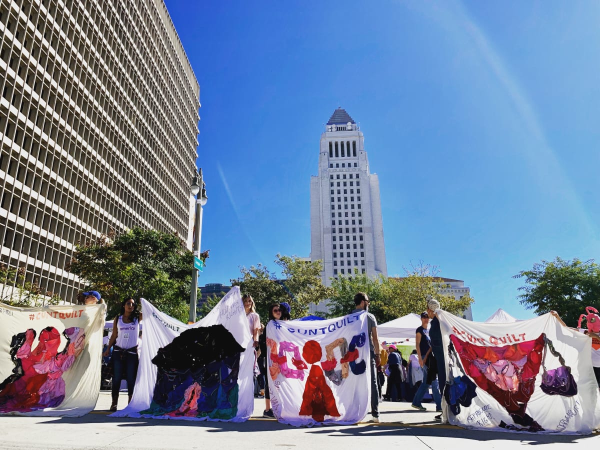 Arpillera Americanx * Cunt Quilt (Traffic) Cunt Congress by Coralina Rodriguez Meyer  Image: Performance of Citizenship by protesters bearing Arpillera Americanx * Cunt Quilt (Traffic) during a Cunt Congress protest at Women's March LA in front of the downtown LA Court House January 19, 2019