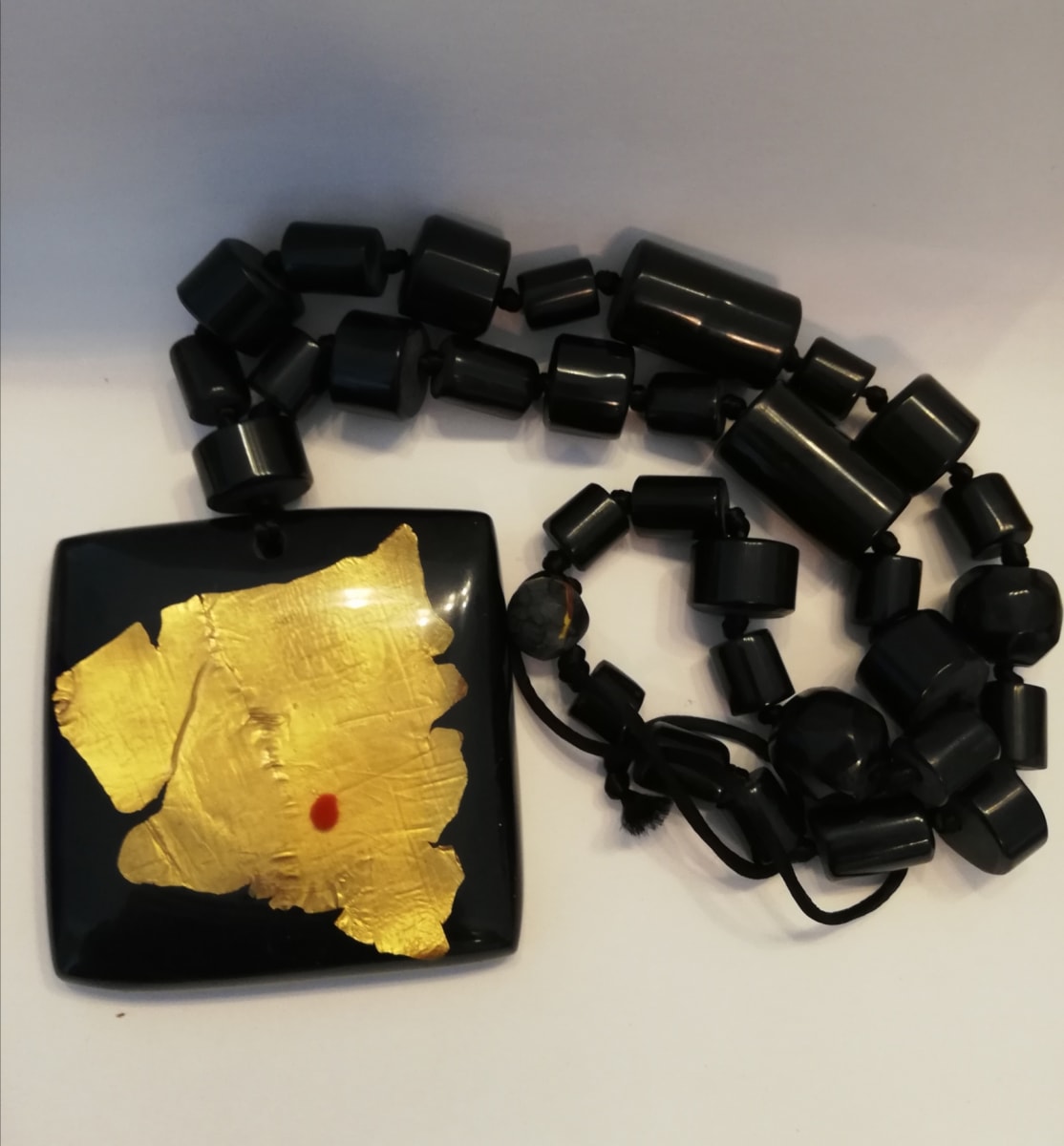 Black Square Pendant with 24 Karat gold leaf inlay, on tube bead necklace.  Image: Black Square Pendant with 24 Karat gold leaf inlay, on tube bead necklace.