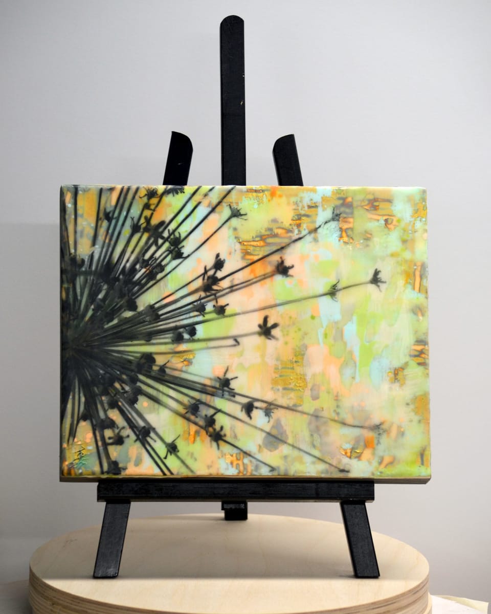 Burst by Kristianne Tefft  Image: This artwork was created by torch fusing clear encaustic medium, various encaustic paints, oil pastels, and pan pastels.  There are also several images burnished into different layers of wax.  The image was taken at Dow Gardens in Midland, MI. 