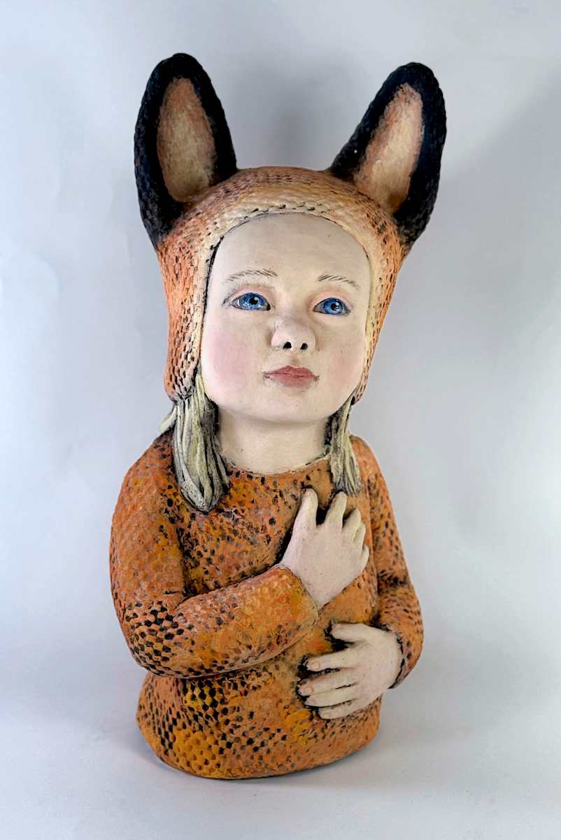 The Listening Heart by Susan Silvester  Image: This ceramic sculpture portrays a young girl in an orange fox-like garment, her expression solemn yet open, her posture quietly reverent. One hand rests over her heart while the other touches her stomach, a gesture that suggests both emotional sincerity and the nurturing of inner life. Her upward gaze carries the intensity of listening beyond herself, as though attuned to something unseen. The fox-hood and dark ears add a subtle, dreamlike edge, hinting at the thresholds between innocence and transformation.

The Listening Heart becomes an allegory of receptivity and introspection. It is a reminder of how we safeguard dreams and remain attentive to the deeper voices within.