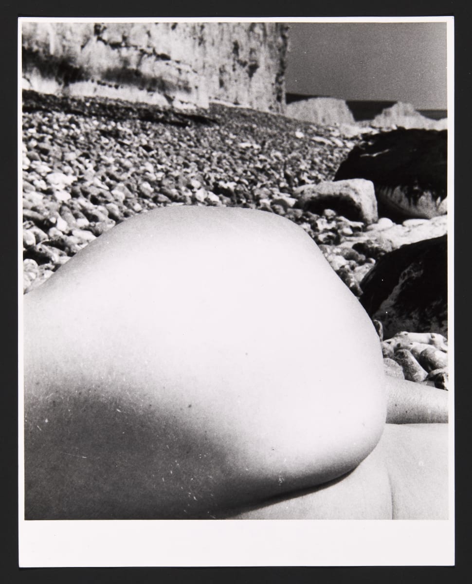 Black and white photograph of close up of body with rocks in background by Bill Brandt 