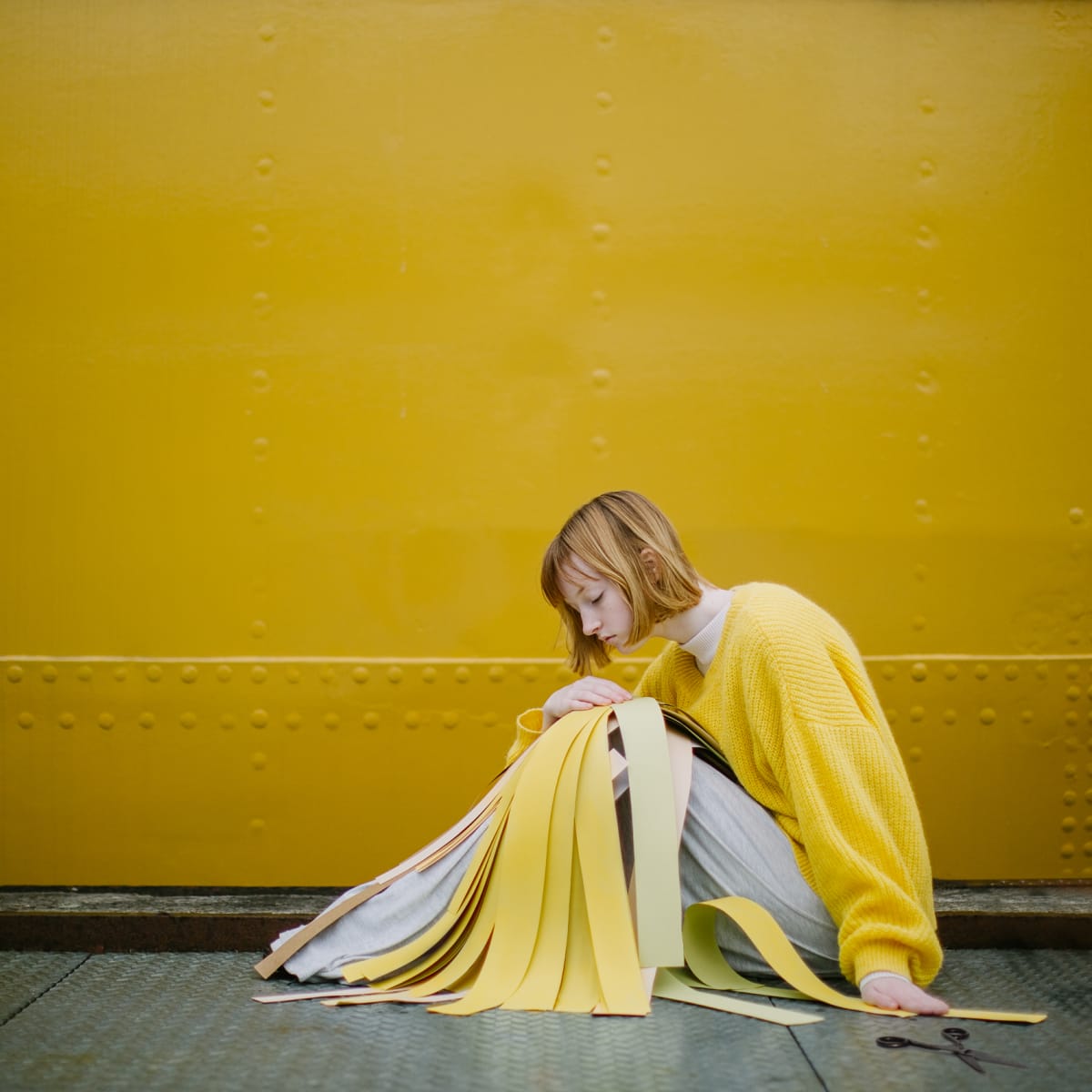Yellow by Dasha Pears  Image: The image pictures a person who did cut off all the narratives that she had about herself and is in a transition phase: she knows that she doesn't want to go back to the past, but is a bit unsure of what the future holds. We all have periods of rumination over some changes that we when through in life: "was it the right thing to do? what if I destroyed my life by doing that?". The truth however is that we have pieces that we can't put back into a sheet, but we can glue something new and absolutely amazing from of them.