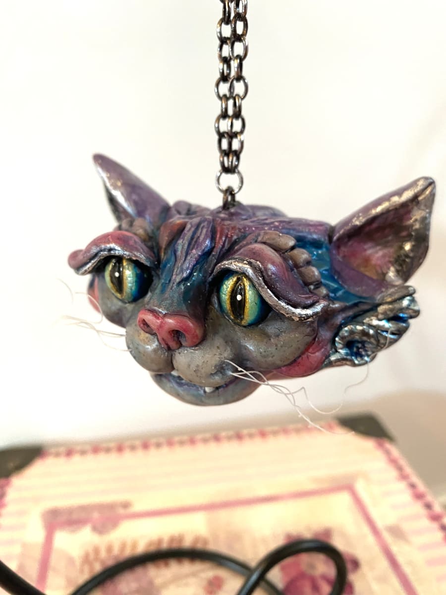 Cheshire Cat Ornament by Marie Young  Image: Original Cheshire Cat ornament hand-sculpted from polymer clay. Accented with silver foil and vibrant alcohol inks.