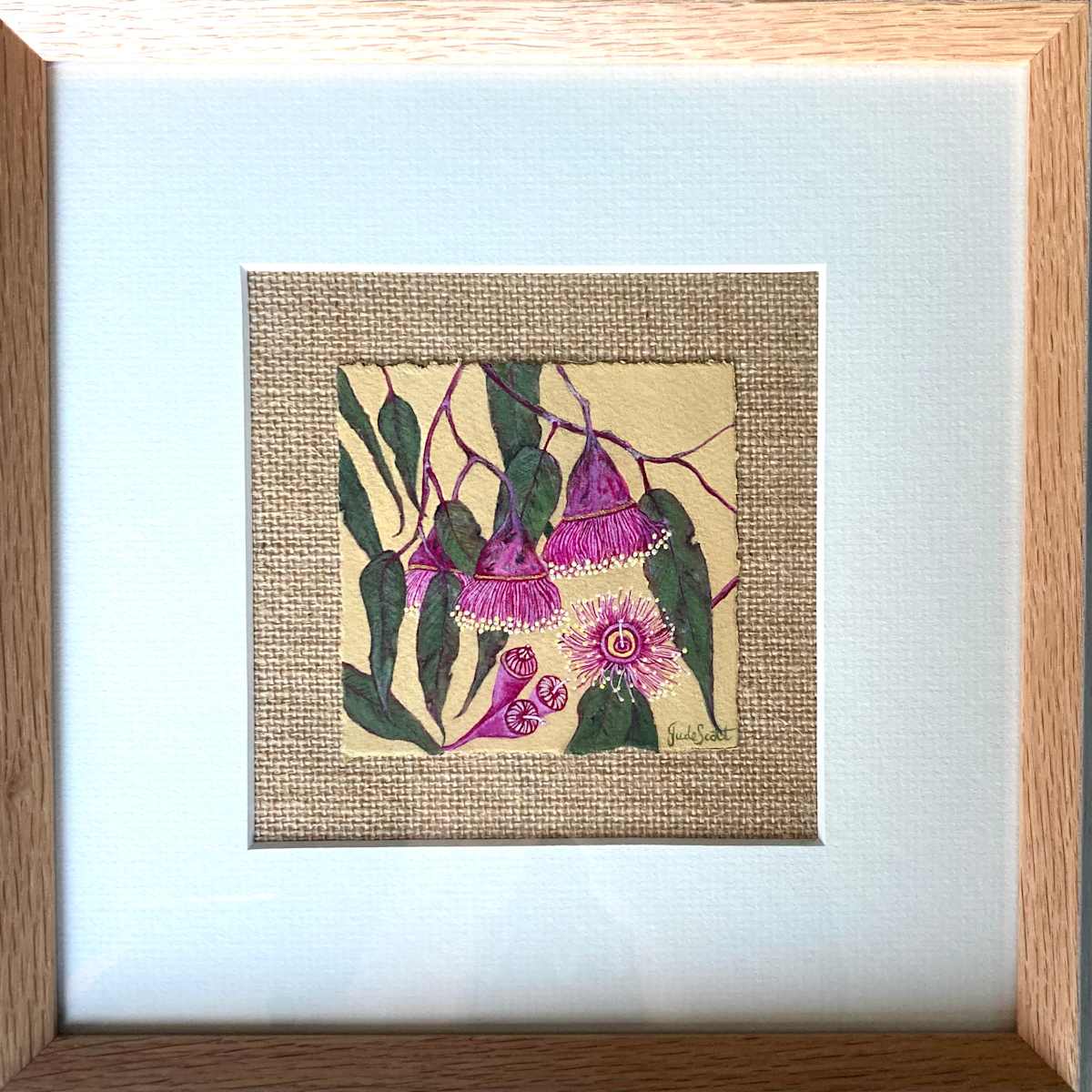 Gum Blossoms by Jude Scott  Image: A mini study of gum leaves and blossoms in various states of bloom.  They are so pretty and delicate, I wanted to capture the different stages in one little painting. I also wanted to create extra visual intererst by layering different textures, from the grained paper with torn edges, to mounting on hession with a textured border in the wooden frame.
