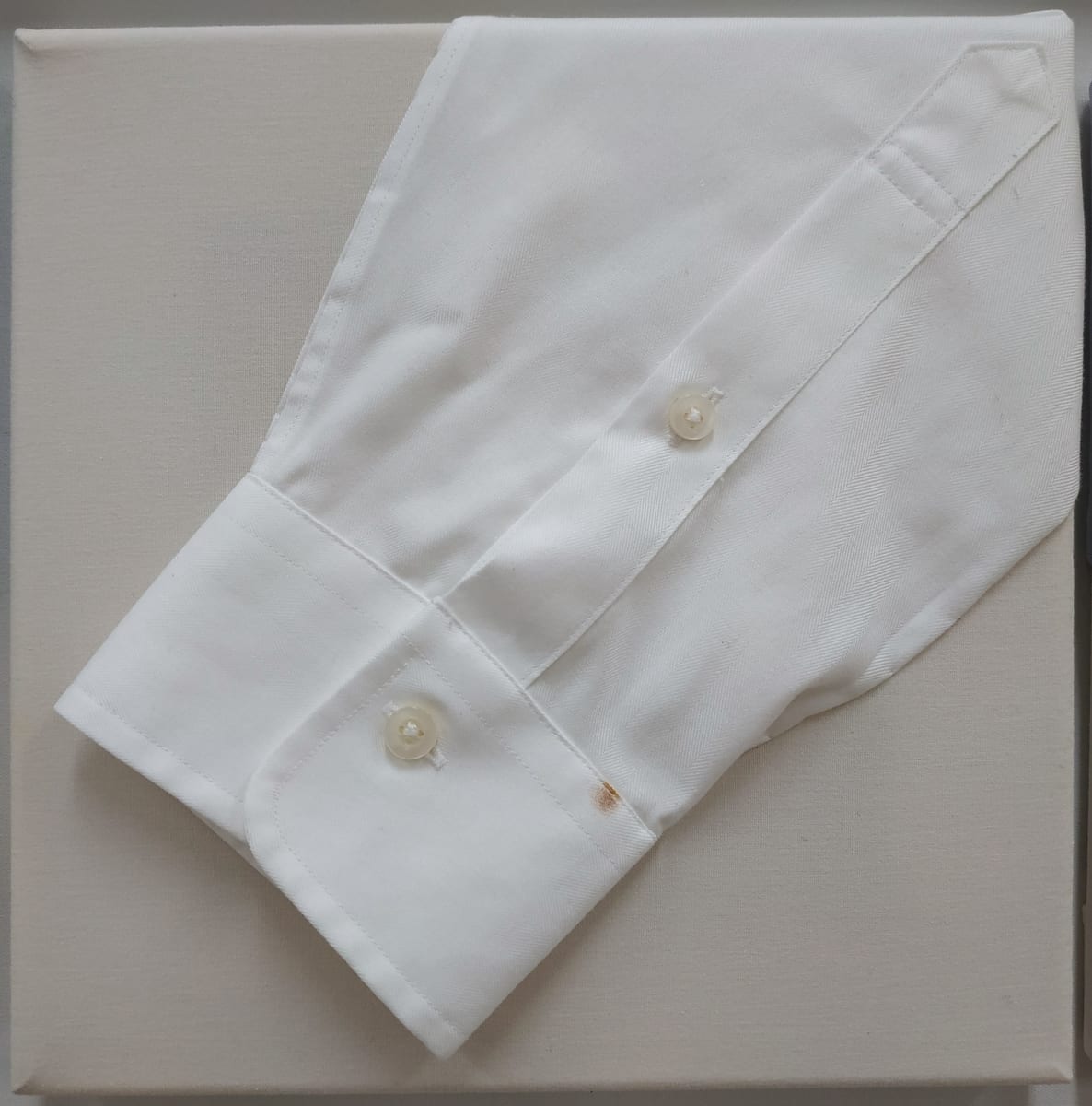 Idiom: On the Cuff by Lesley Turner  Image: Lesley Turner, 'Idiom: On the Cuff', 2020, 9"x9". Cotton shirt cuff, plastic buttons, bedsheet, polyester thread. This idiom originated from the practice of bartenders recording customers' bar tabs on their shirt cuffs.