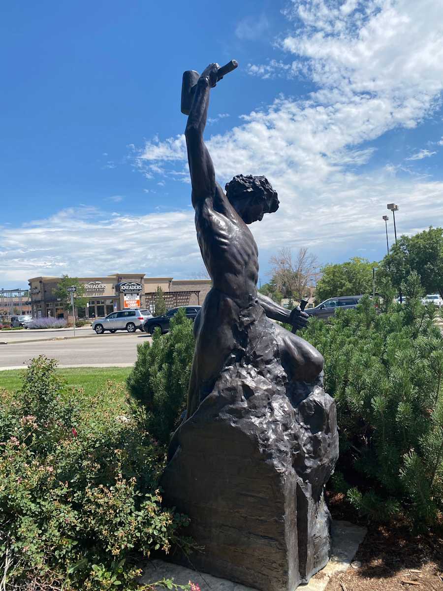 Self Made Man (Permanent Public Art) by Bobbie Carlyle  Image: On display at Living Wheel Park, this bronze sculpture by Colorado artist Bobbie Carlyle depicts a man carving himself out of a block of stone… carving his character, carving his future.