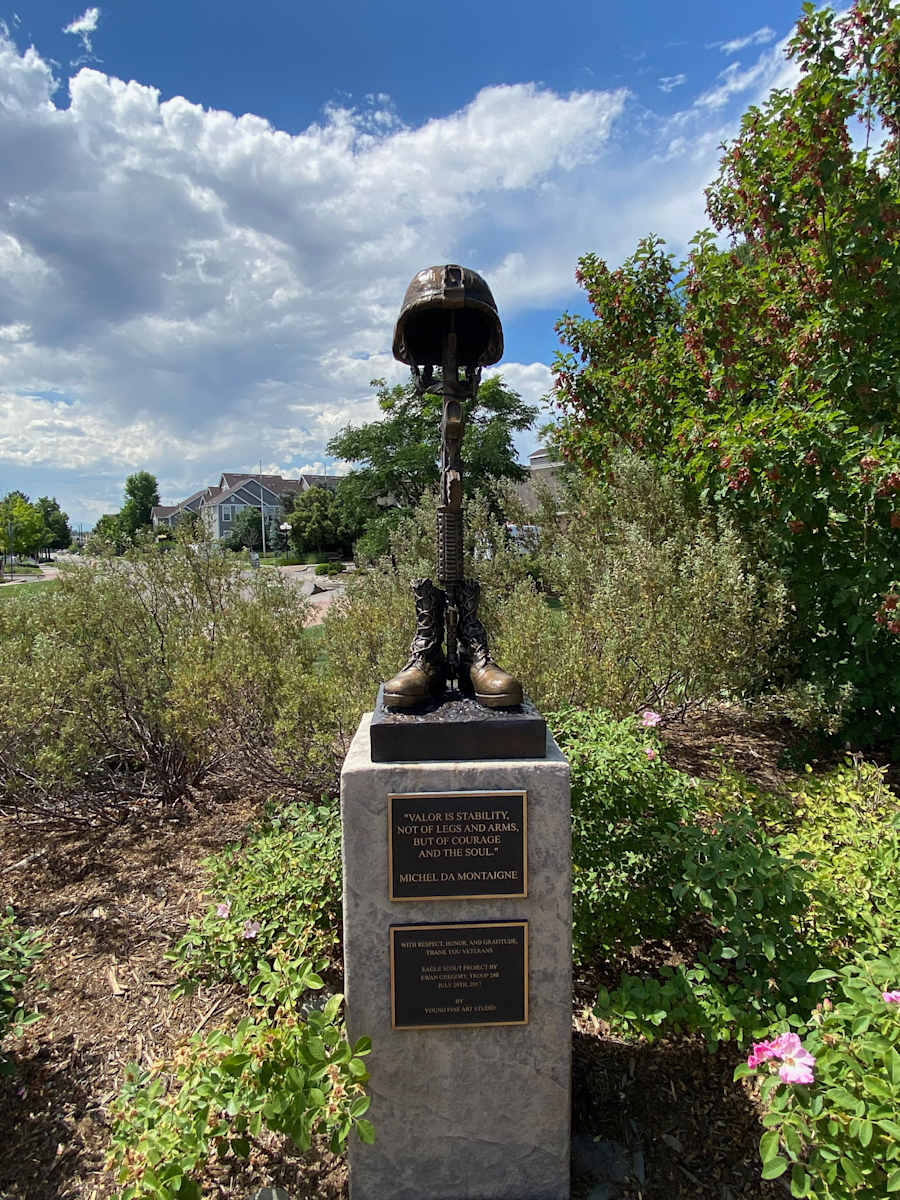 Battlefield Cross (Permanent Public Art) by Richard Young  Image: Created by artist, Richard Young and his studio, Young Fine Arts, Inc. and donated by Ewan Gregory, this 36″ x 16″ x 16″ bronze sculpture sits on a pedestal at Living Wheel Park, a location created as a dedication to and remembrance of our veterans. The sculpture honors the ultimate service of our fallen heroes and calls the public’s attention to the lives they valued and the sacrifice they share.