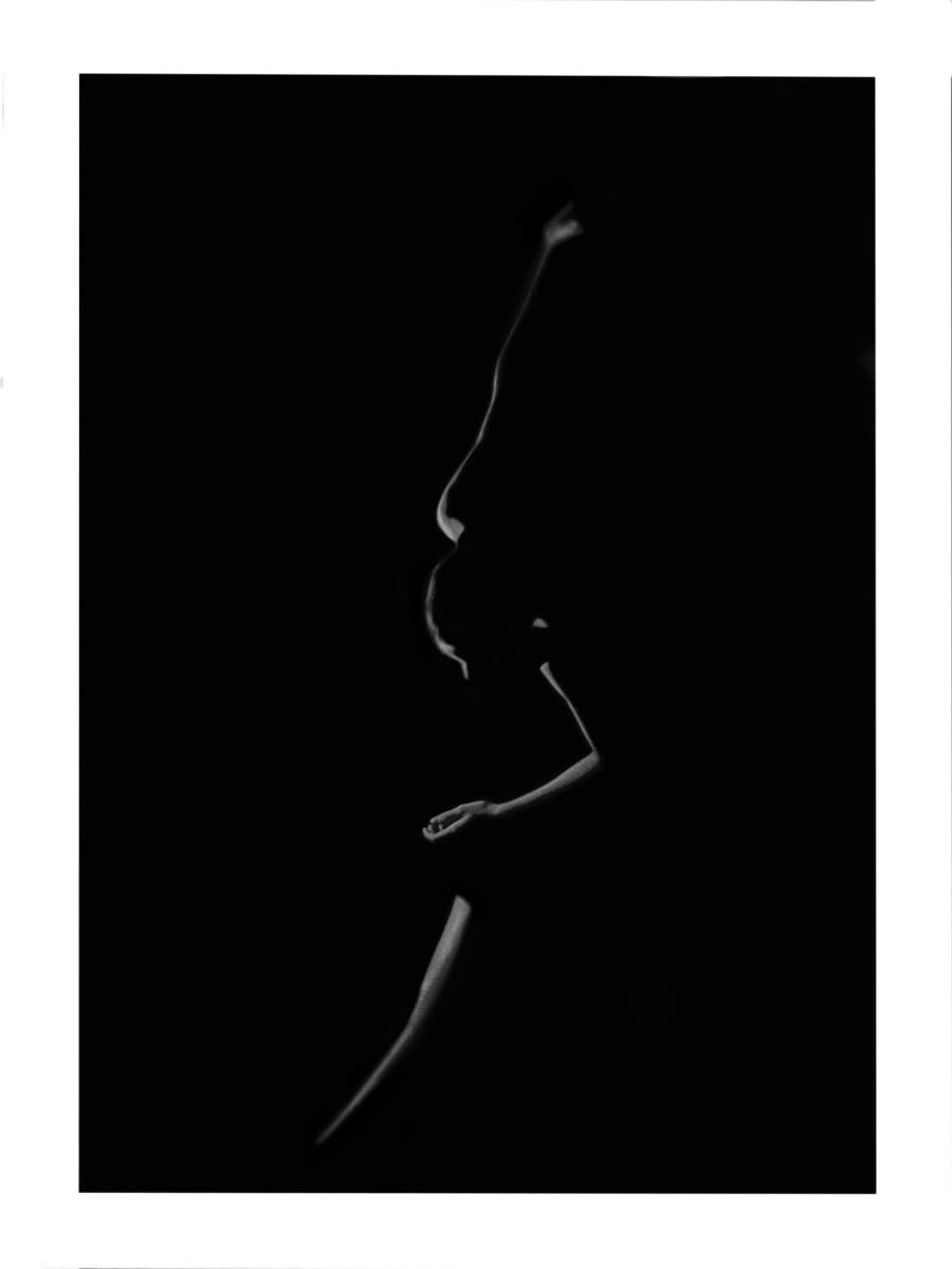Dancing Silhouette by Brittany Barnett  Image: A white outline of a girl against a black background. The light silhouettes her face, arms and legs. The dark shadows carve shapes into her form giving the most basic outline of her stance. The girl leans forward with her left leg crossed in front of her, her left arm held in front of her body, and her right arm thrown high above her head, twisting as far back as it will go.