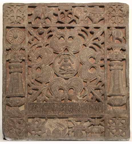 Sihanāṃdikā Āyāgapaṭa  Image: Mathura, India

This ayagapata named so after the donor has as the central image a Jina seated in a meditative posture on an elevated platform. A parasol embellished with garlands framing the Jina’s head and shoulders indicates his venerable status. Surrounding the Jina in four cardinal directions are four three-pronged ω -shaped forms known as nandyavartas (indicating the three jewels of Jain practice: right faith, right knowledge and right conduct). The bottom and top registers carry symbols including a pair of fish, an unending knot (shrivatsa), a pitcher, an auspicious seat, and an overflowing pot, that eventually developed into a set of eight auspicious symbols signifying good fortune and prosperity. 