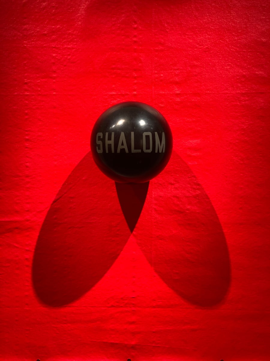 Shalom by Charlie Milgrim  Image: The word Shalom, or peace in Hebrew, juxtaposes with the violent red background.
