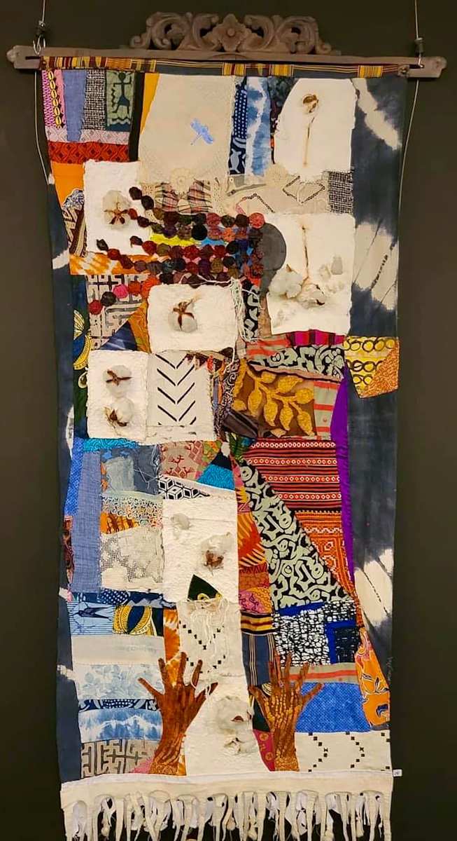 HONORING THE OLD WAYS by ROSALIND NZINGA VAUGHN-NICHOL  Image: HONORING THE OLD WAYS 2022-23.
Mixed-media quilt. Textiles, handmade paper, with cotton stalk inclusions, backed with Indigo dyed textile, hung from a carved wood panel 76” H x 33” W x 1"D.