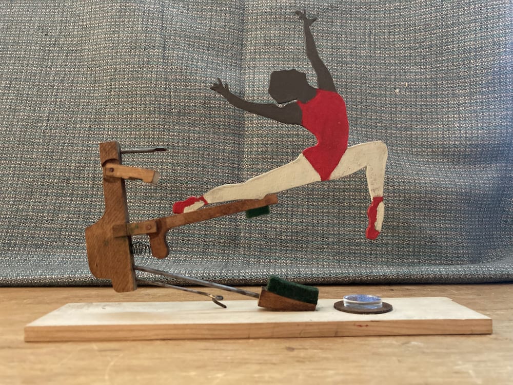 Ballet Dancer Assemblage by Mark Johnston  Image: Hand painted Ballet Dancer suspended from piano damper mounted to Walnut base with spring action dancing.  Toe taps on blue earth like circle.