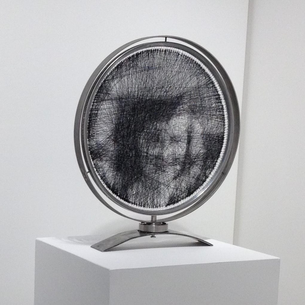 Thread Portrait by Mark Johnston  Image: Thread Portrait constructed from black sewing thread inside of Aluminum bicycle wheel frame mounted inside circular steel sculpture