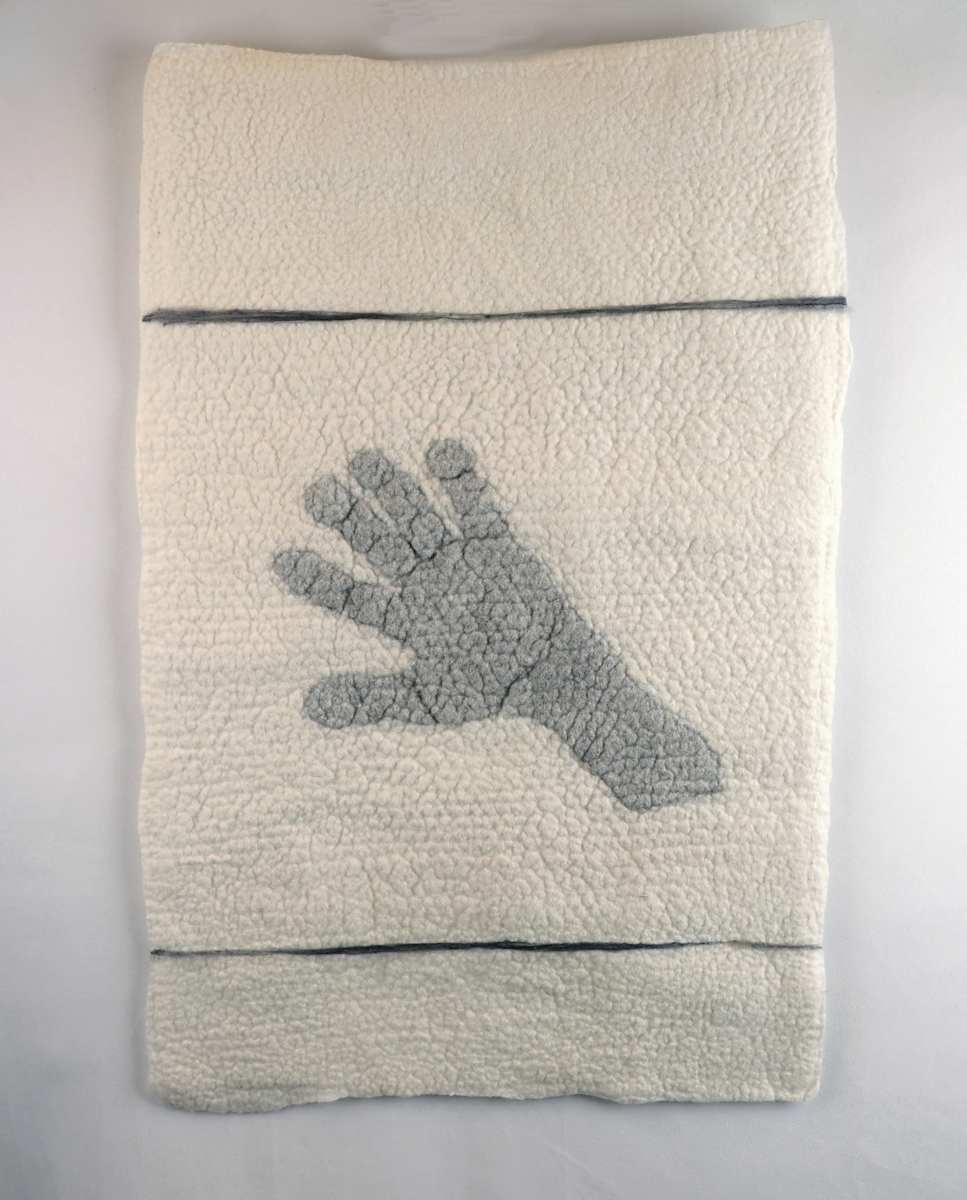 Reach by Jennifer Angelo  Image: The outstretched hand in this artwork speaks of sharing, a universal gesture that transcends language. Crafted with care through wet felting, each fiber becomes a thread connecting us. This piece evokes the spirit of community, where open hands symbolize openness and the desire to share experiences, knowledge, and love.