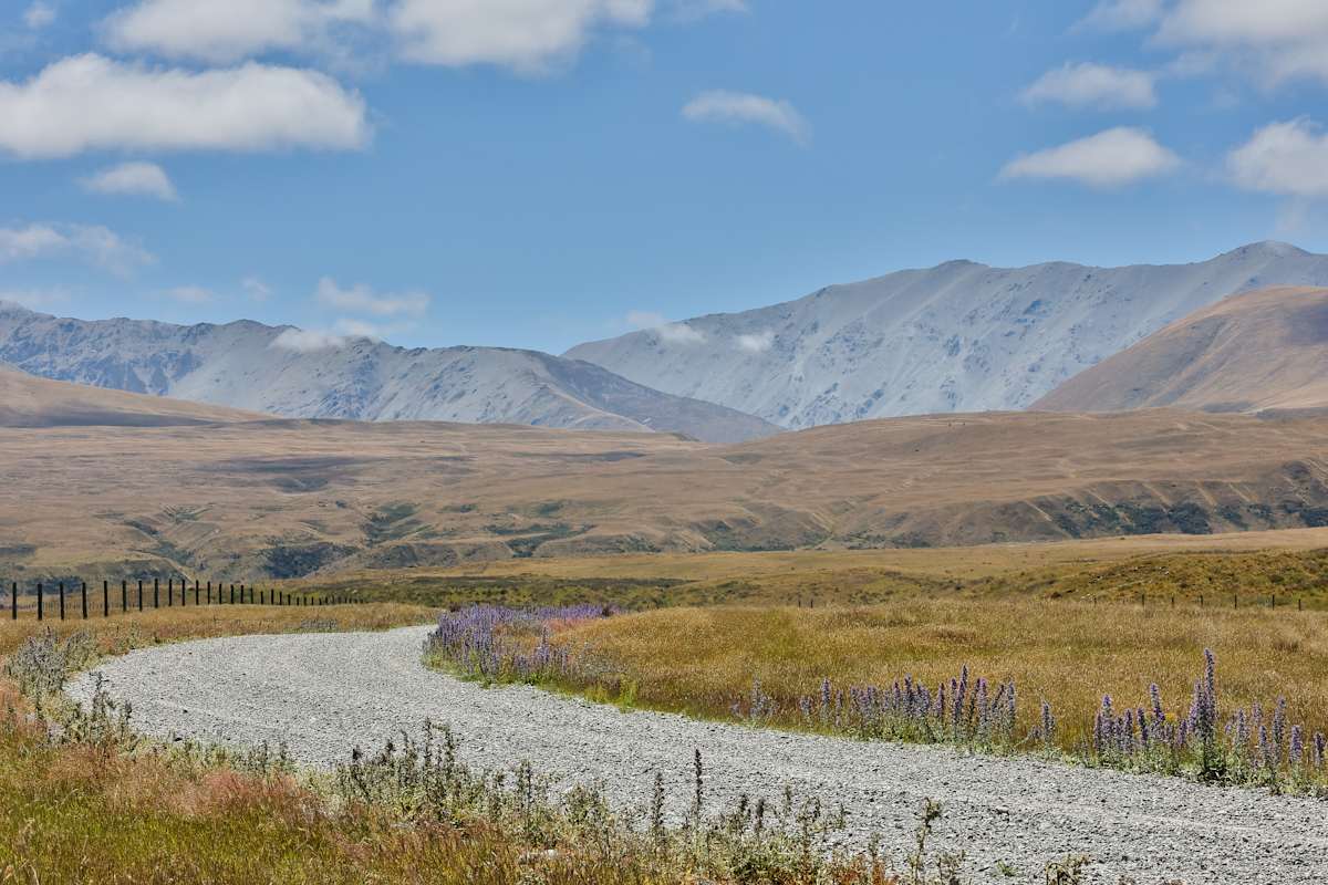 Path through rolling hills by EB Photography  Image: Gravel road curving around mountains at Lake Tekapo