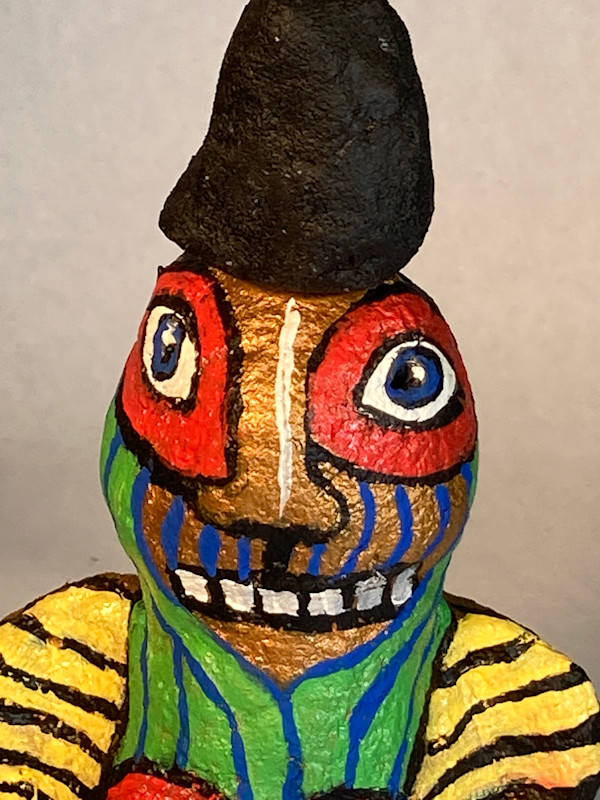 Gold face with red eyes and black hat by Jennifer Taylor