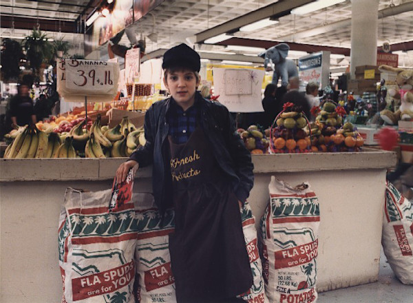 Broadway market: boy in front of fruit stand by Marion Faller