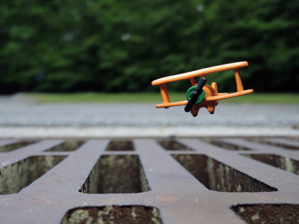 Inches Above Earth Series "Approximate Altitude 5.3 Inches " (Orange Biplane over Metal Grate) by Michael Reese
