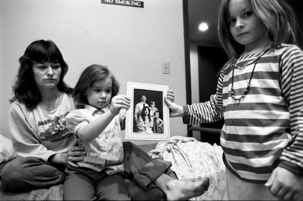 Mary + her daughters holding a family portrait with their father, Minneapolis, from Living with the Enemy by Donna Ferrato