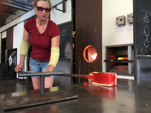Artist Susan Madacsi marvering a fused glass billet before pulling murrini cane from it. by Susan Madacsi