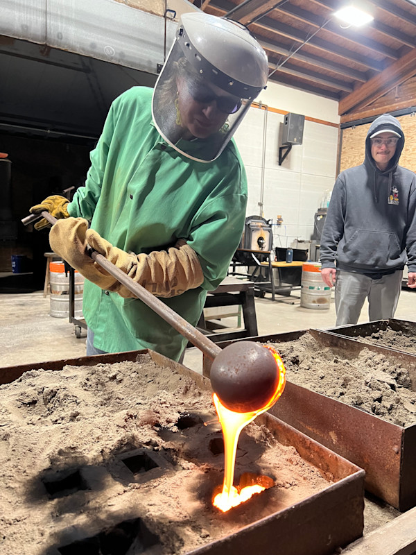Artist Susan Madacsi ladling glass into a sand mold. by Susan Madacsi, Image 5.