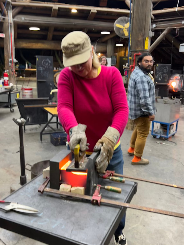 Artist Susan Madacsi shaping hot ladled glass into a copper form. by Susan Madacsi