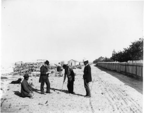 Crab pots stacked on the beach, Shaker church in the bckground, Jamestown, WA, 1900 by Charlotte Watts