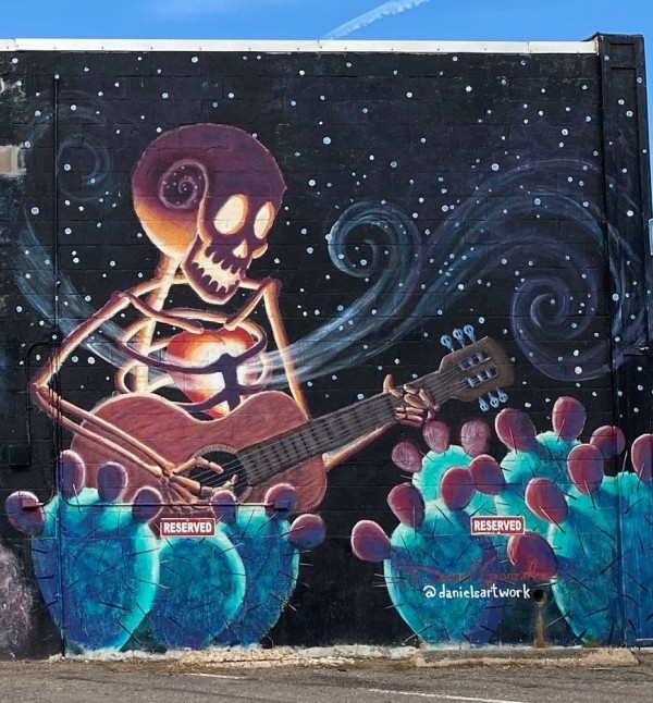 Untitled - skeleton playing guitar near cactus by Daniel Gonzalez