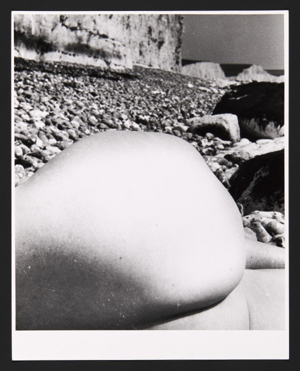 Black and white photograph of close up of body with rocks in background by Bill Brandt