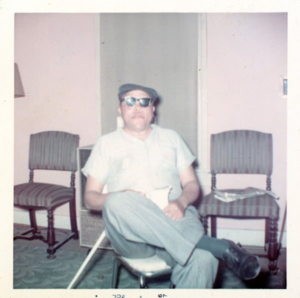 Man in glasses sitting in pink room by Unknown