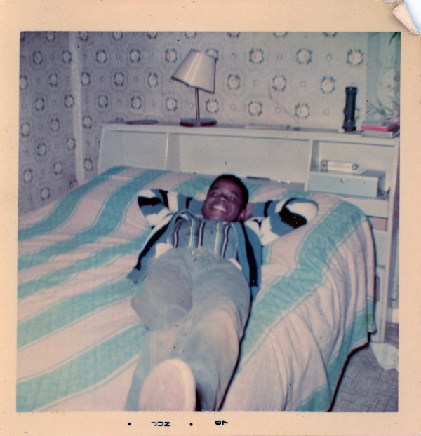Boy lying on striped bedcover by Unknown