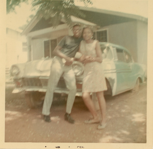 Couple leaning against car by Unknown