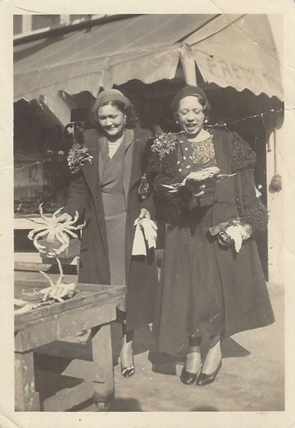 Two women holding crabs by Unknown
