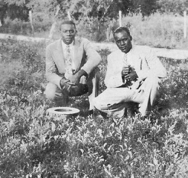 Two men crouching in a field by Unknown