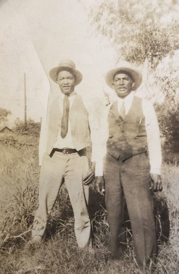 Two men wearing hats standing in a field by Unknown