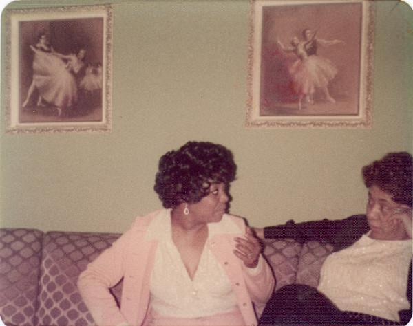 Two women on sofa with ballet pictures on the wall by Unknown