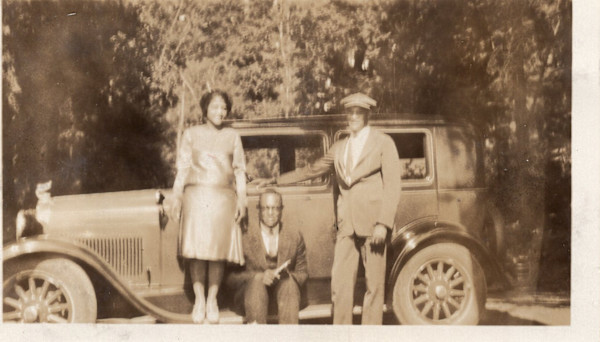 Trio posed next to automobile by Unknown