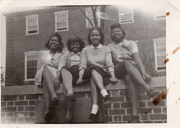 Four young students sitting on wall by Unknown