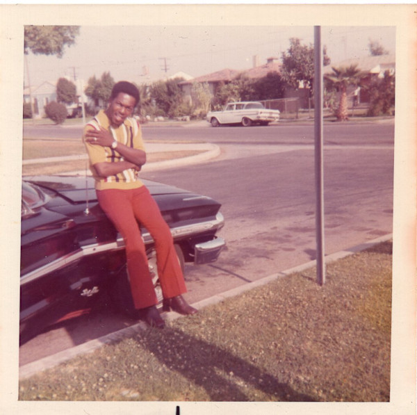 Man leaning on car, arms crossed over chest by Unknown