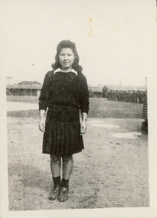 Japanese? girl standing near army barracks by Unknown