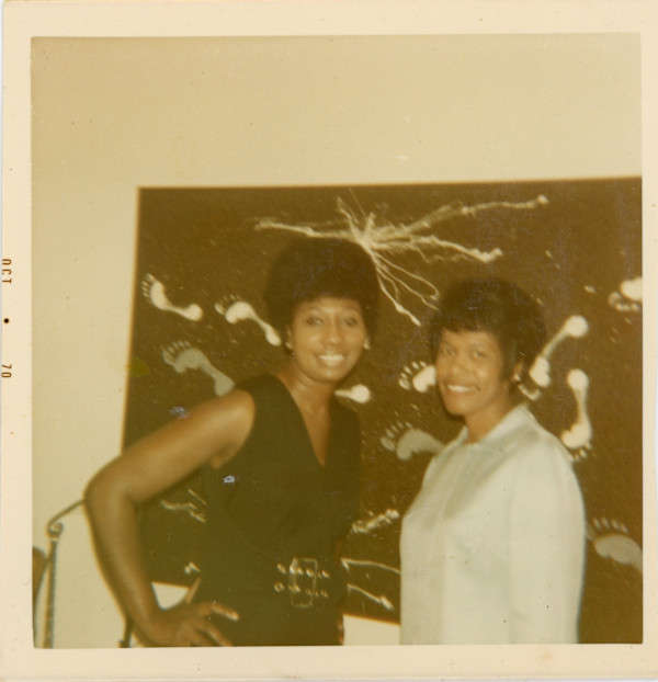Woman in blue dress and friend next to artwork with footprints by Unknown