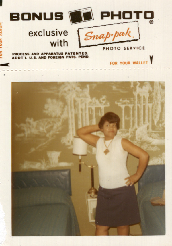 Bonus print of woman with arm up posed in front of mural by Unknown