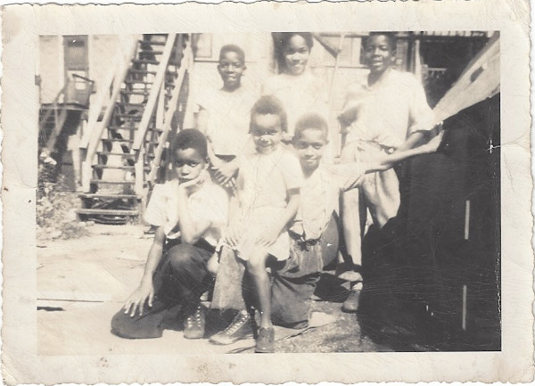 Young girl posing with boys by Unknown